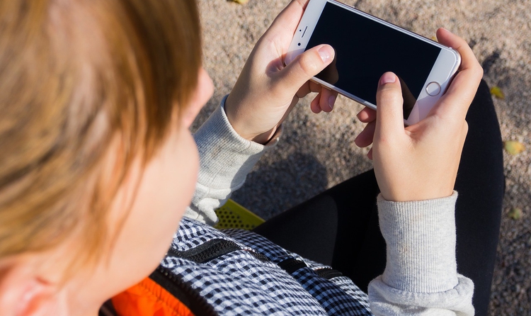 Un infant interactua amb un telèfon mòbil.