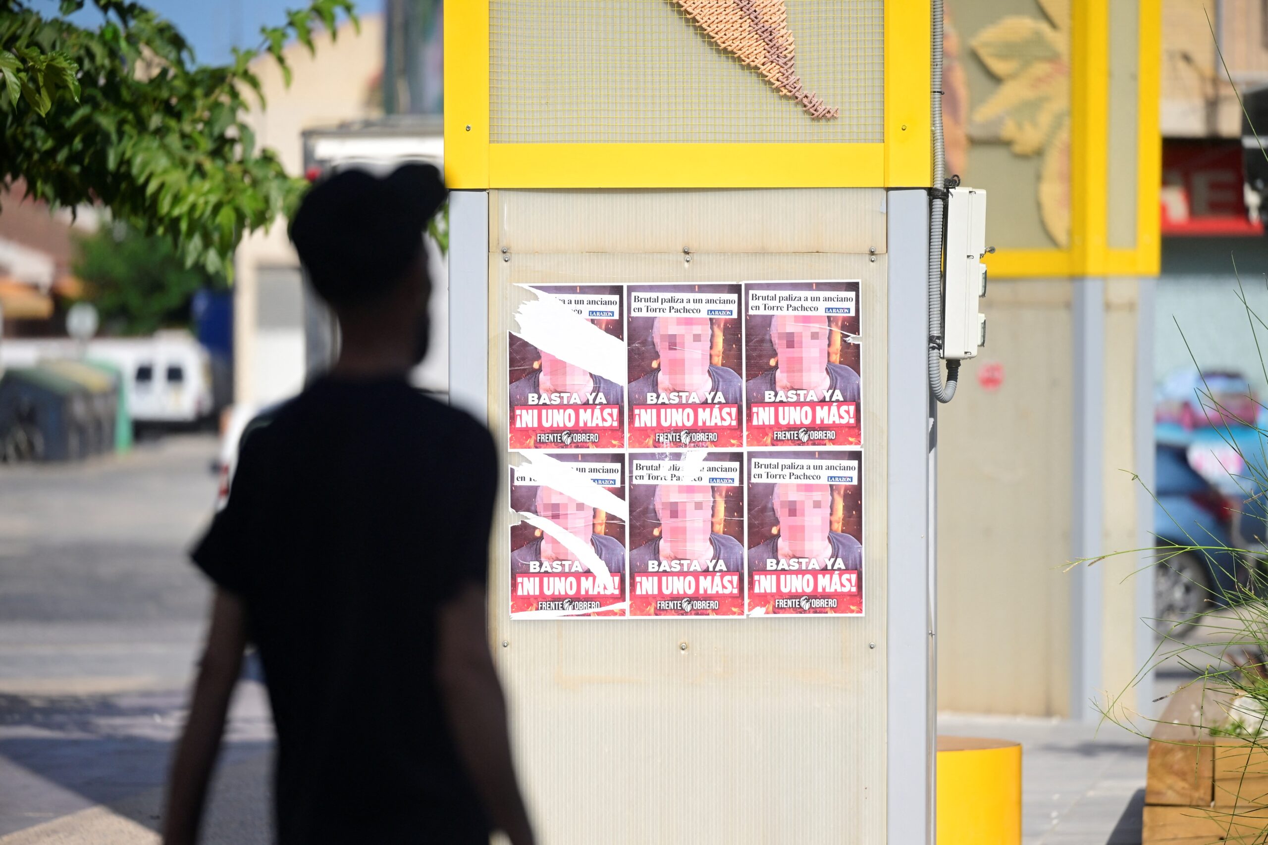 A migrant walks past posters reading 'Stop, not a single one more' on the fourth day of anti-migrant unrest in Torre Pacheco, southeastern Spain, on July 15, 2025. Spanish police have arrested nine people over rare anti-migrant unrest that rocked the town of Torre Pacheco, authorities said on July 14. Three nights of violence erupted on July 11 after a 68-year-old man told local media three youths of North African origin had beaten him up in the street of the southeastern town.
(Photo by JOSE JORDAN / AFP)