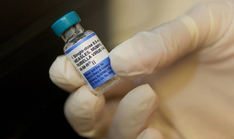 Una dosi d'una vacuna agafada per una mà amb guants