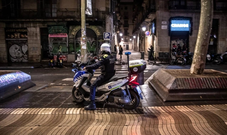 Un agent de la guàrdia urbana de Barcelona informa els vianants sobre la introducció d'un toc de queda a la Rambla. (Foto d'ANGEL GARCIA / AFP) inmigrantes delincuencia