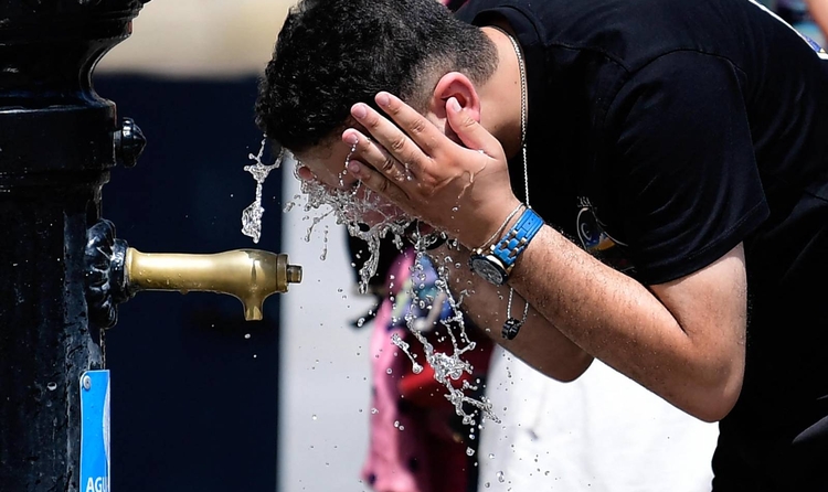 Un home es refresca en una font durant l'extrema onada de calor a Sevilla que supera els quaranta graus, a Sevilla el 12 d'agost de 2025. (Foto de CRISTINA QUICLER / AFP)